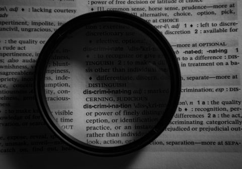 Image of an magnifying glass on a paper with words.