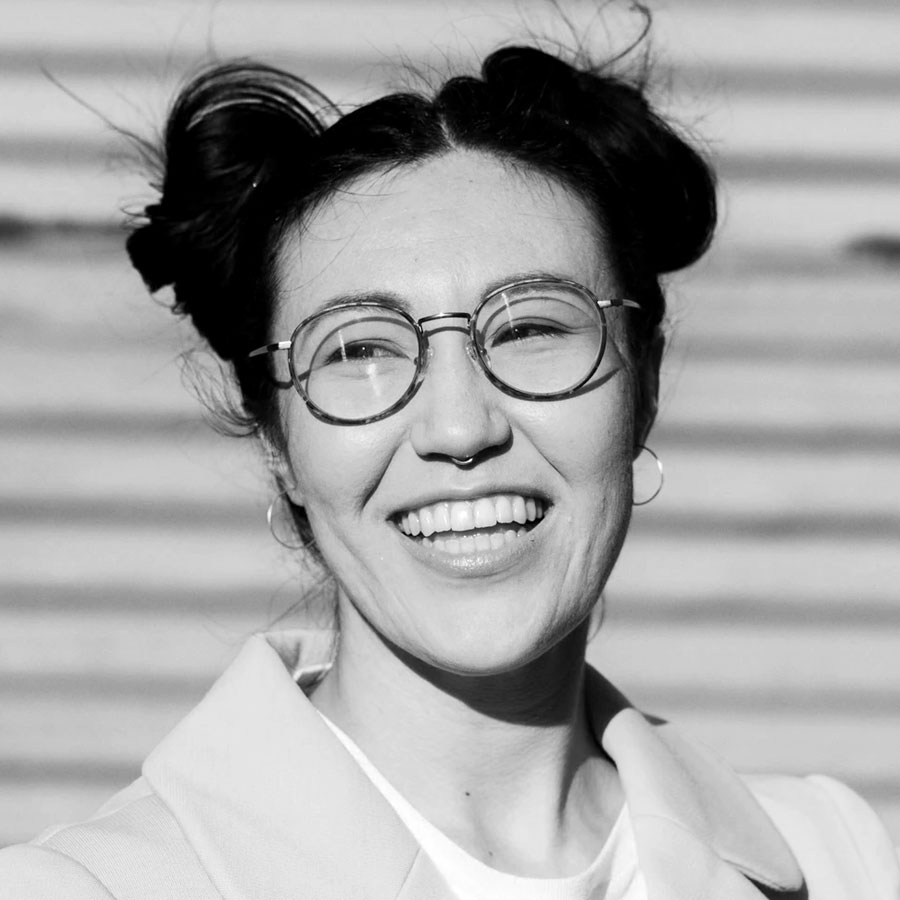 Woman with round glasses and her hair in two buns laughing.